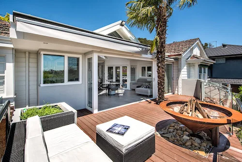 A wide shot of opened Upvc windows overlooking outdoor furniture and firepit in sunny Melbourne, Australia with large upvc door windows installed